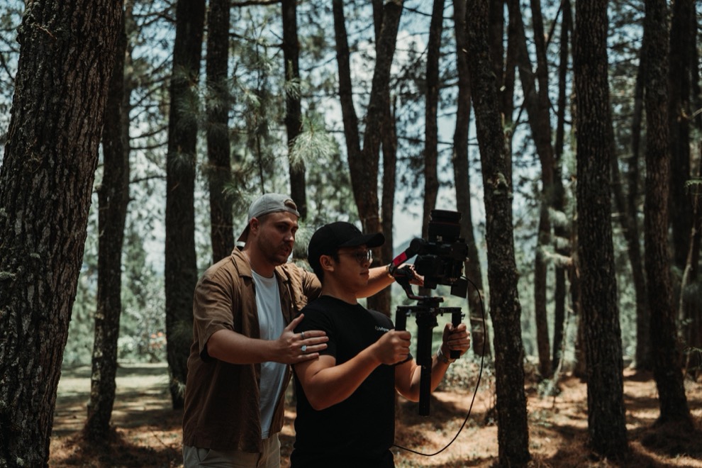 Matt directing a gimbal operator among tall pines