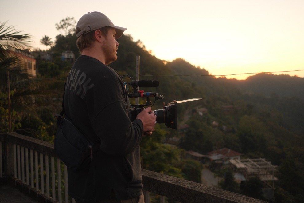 Matt holding a rigged cinema camera on a hillside terrace at dusk